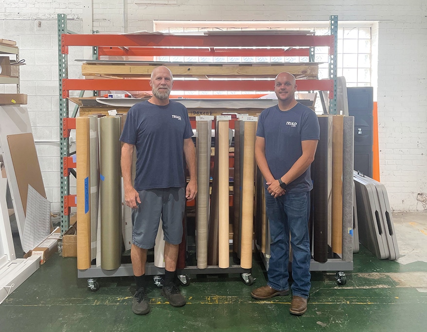 PIP Triad’s 3M Preferred Installers Jody Belangia (left) and Brandon Williams (right) standing in front of several rolls of 3M Di-Noc used for past jobs.