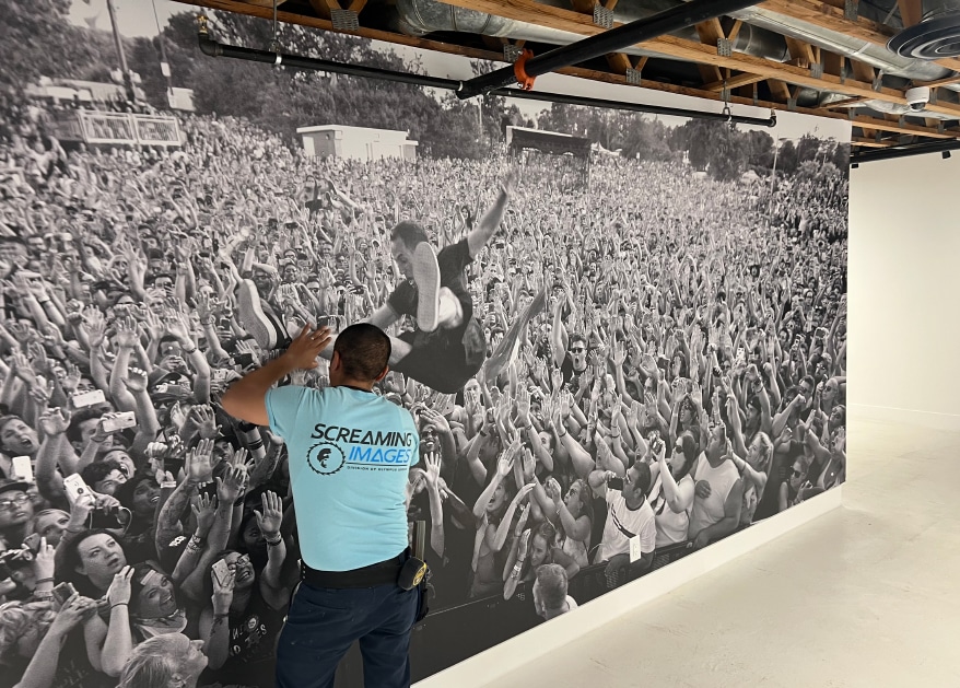 Gabe Chavez, one of two Screaming Images installers, smoothing out a wallcovering for the just-opened Punk Rock Museum in Las Vegas.